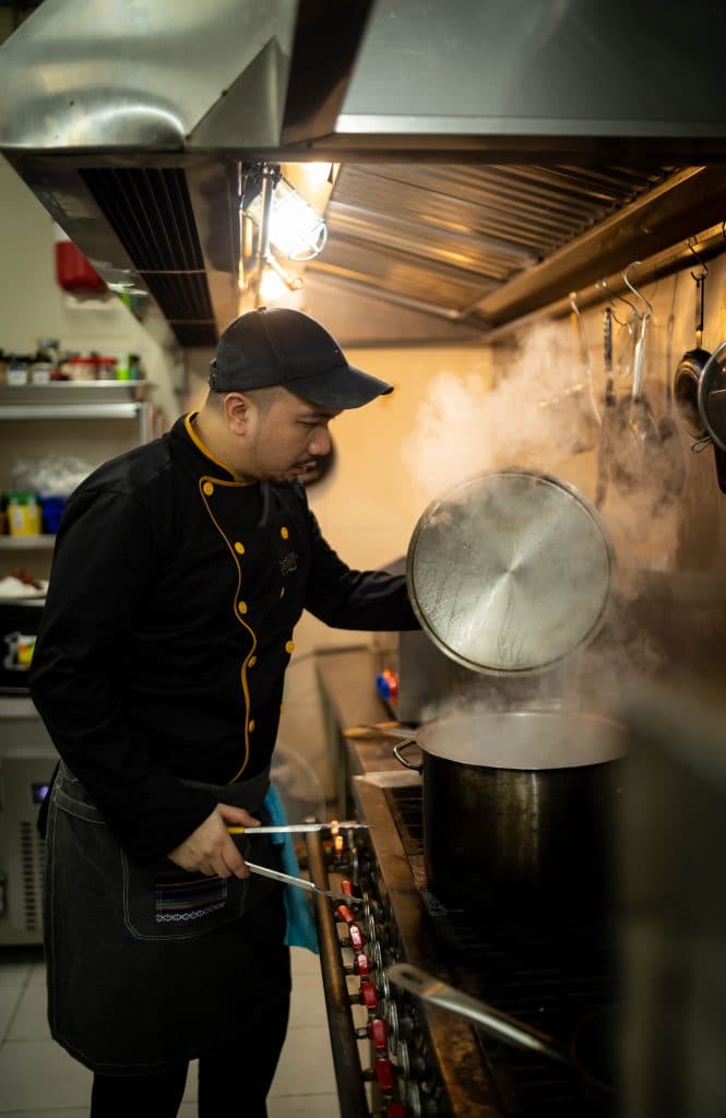 Chef lifting the lid off a steaming pot