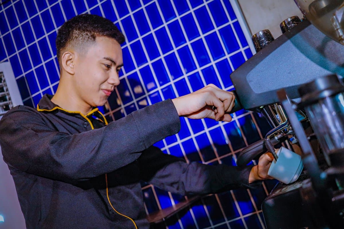 Barista pouring coffee against the blue-tiled bar
