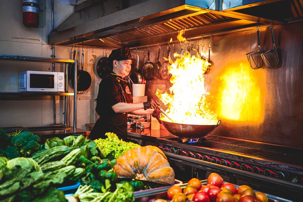 Chef tossing a flaming wok in the kitchen